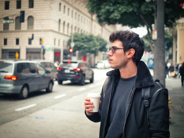 迷人的年轻人在现代城市中心喝着纸杯咖啡 穿着皮夹克 — 图库照片