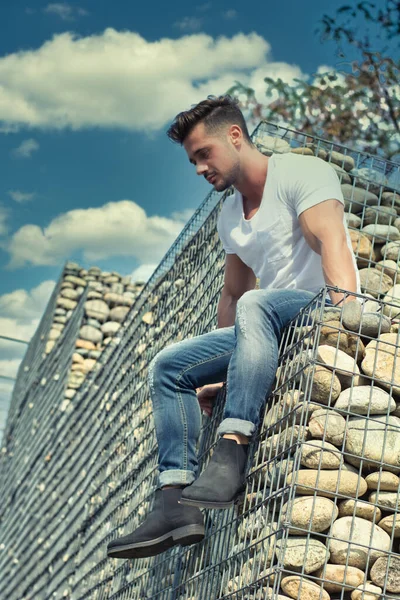 ハンサムな若い男が石のブロックに横になり 下を見下ろす — ストック写真