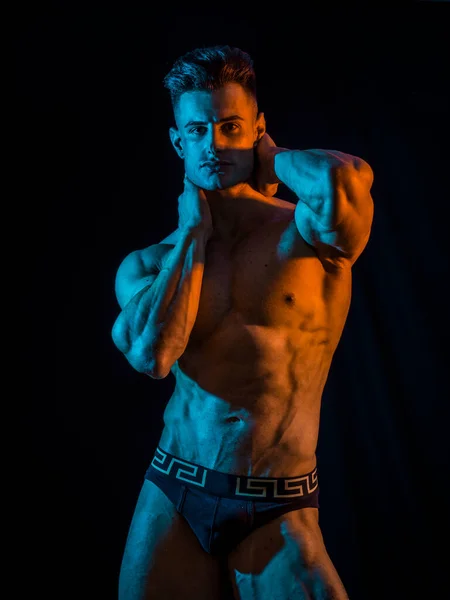 年轻英俊的男性健美运动员在演播室拍摄 与戏剧性的照明 穿着短裤 — 图库照片