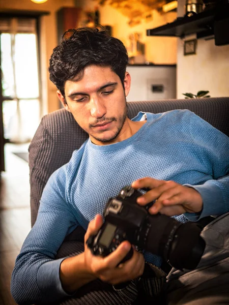 Przystojny Młody Mężczyzna Fotograf Gospodarstwa Patrząc Jego Profesjonalny Fotokamera Domu — Zdjęcie stockowe