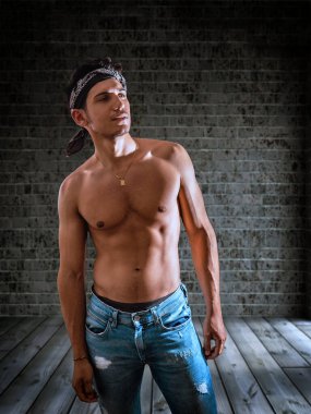 Seksi yakışıklı genç adam boş odasında üstsüz duruyor, kameranın önünde kafasını kaldırıyor.