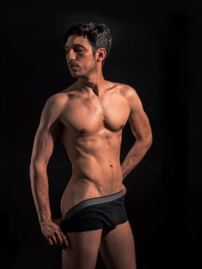 Muscular man pulling down underwear to show his butt, in studio shot