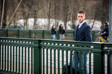 Takım elbiseli ve kravatlı bir adam bavul tutuyor.