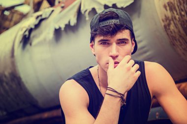 Şapka takan ve elini ağzına alan genç bir adam.