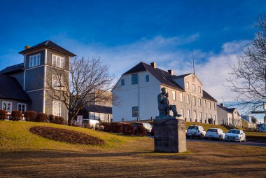 Büyük beyaz bir binanın önünde bir heykel.