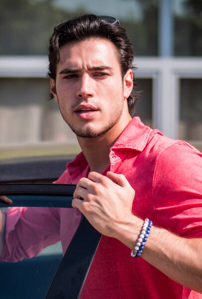 Мужчина в розовой рубашке, держащий машину. Фото мужчины в розовой рубашке, держащегося за дверь машины