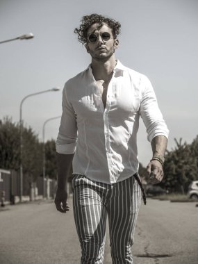 Boş bir caddede yürüyen yakışıklı bir adamın fotoğrafı.