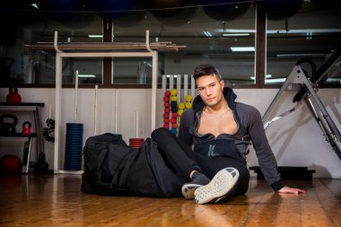 Spor salonunda yerde oturan bir adam.