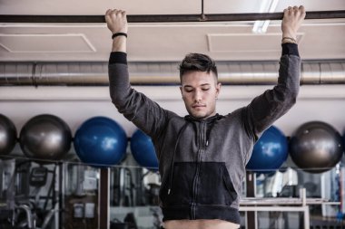 Spor salonunda kolunu kaldıran bir adam.