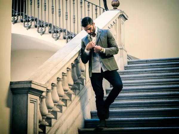 A man in a suit is walking down a set of stairs. Photo of a man descending a grand staircase in a stylish suit
