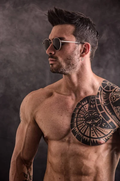 A man with a sun tattoo on his chest. Photo of a muscular man showcasing a sun tattoo on his chest