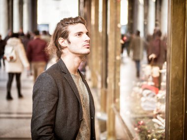 Camcı dükkanının önünde duran bir adam, içeriye bakıyor.