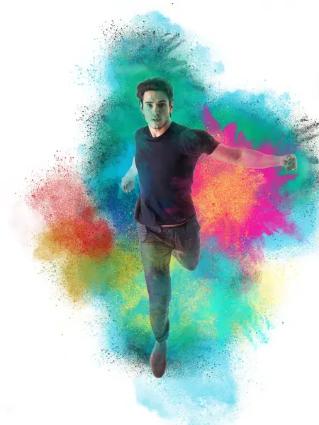 A man in a black shirt is running through colored powder. Photo of a young and attractive man joyfully running through a vibrant cloud of colorful powder