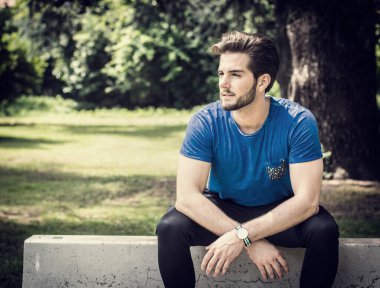 Parktaki çimento tezgahında oturan bir adam. Şehir parkında beton bir bankta oturan bir adamın resmi.