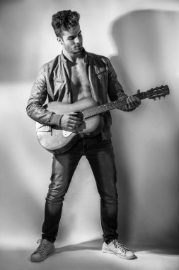 Çıplak gövdesi açık ceketli, turuncu gitarlı, üstsüz bir adam.