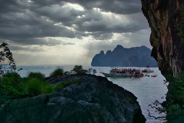 A boat in the water near a rocky cliff. Photo of a boat sailing near a beautiful rocky cliff in Thailand