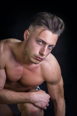 Tişörtsüz bir adam dizlerinin üstüne çökmüş.