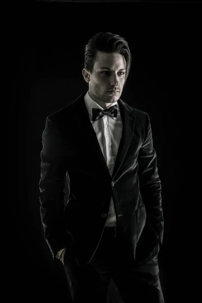 A man in a tuxedo poses for a picture