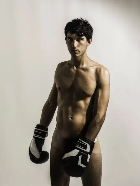 A totally naked young athletic man with no shirt wearing boxing gloves. A Handsome, Athletic Young Man Ready for Action