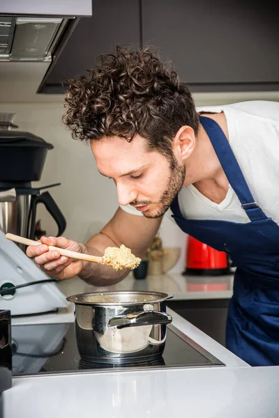 stock image A man in an apron is eating from a pot, tasting his next dish. A Hungry Chef Indulging in a Delicious Meal