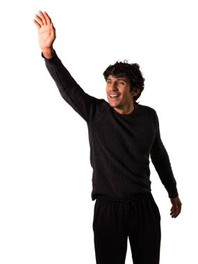 Siyah gömlekli ve siyah pantolonlu bir adam tek eliyle selam veriyor, selam veriyor, stüdyo çekiminde elini kaldırıyor.