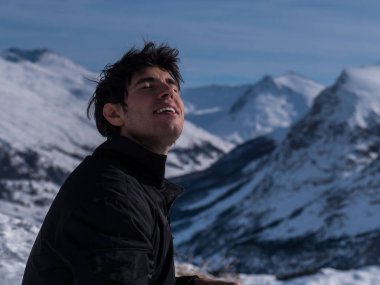 Karla kaplı bir dağın tepesinde oturan bir adam