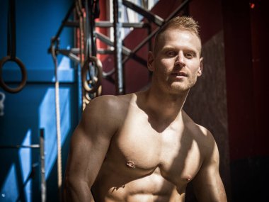 Spor yaparken spor salonundaki bankta dinlenen yakışıklı kaslı genç adam.