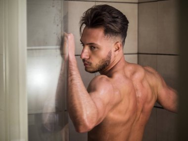 Çıplak Atletik Genç Adam, Cam Kapı 'ya yaslanırken Dinlenmek İçin Banyo' da Banyo Yapıyor.