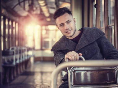 Oturan kış elbiseler giymiş genç yakışıklı adam boş tramvay ya da şehir, eski otobüs sürme