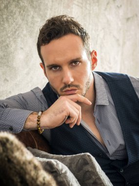 Evde tişört ve boncuklu bilezikler takan çekici bir genç.