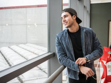 Evin içinde kot ceket ve beyzbol şapkası giyen çekici bir genç adam.