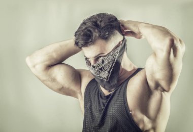 Hırsız ya da haydut maskesi takmış yakışıklı, kaslı bir genç.