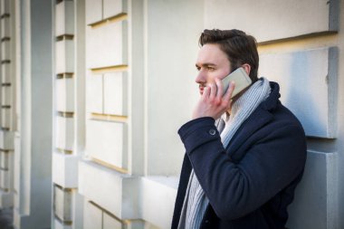 O, zarif eski tarihi binanın arkasına ile Avrupa şehri ortamda açık elinde olduğunu bir cep telefonu üzerinde karanlık kat ayakta ve seyir trendy yakışıklı