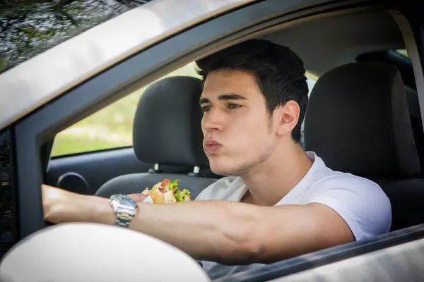 Joven Hombre Guapo Conduciendo Coche Mientras Come Comida Tráfico Fotos de stock libres de derechos