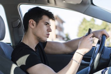 Dikkatsiz yakışıklı genç adam ile meşgul onun cep telefonu iken sürüş araba.