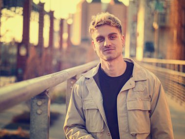 Gün batımında şehir merkezinde bir korkuluğun yanında güvenle duran genç bir adam. Sarı saçları ve mavi gözleri, o sıcak günün tadını çıkarırken onun cazibesini arttırıyor..