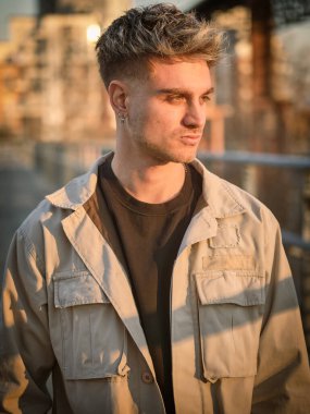 Çarpıcı sarı saçlı ve mavi gözlü genç bir adam gün batımında şehir yolunda yürürken görülüyor. Sıradan bir kıyafet giyer. Kendine güveni ve cazibesi vardır. Anın tadını çıkarır..