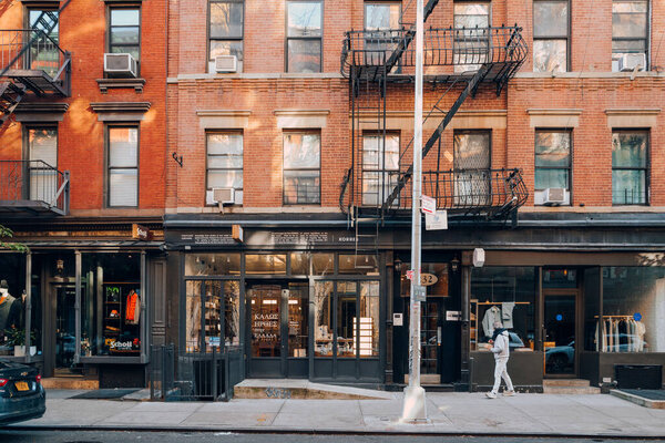 New York, USA - November 21, 2022: Row of shops on Elizabeth Street in Nolita, a charming and upscale area of Manhattan famous for its shops and restaurants, man walks in front.