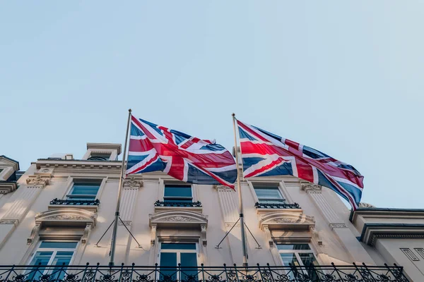 英国伦敦一幢建筑物外的柱子上飘扬着两面欧盟杰克英国国旗的低角度图像 — 图库照片