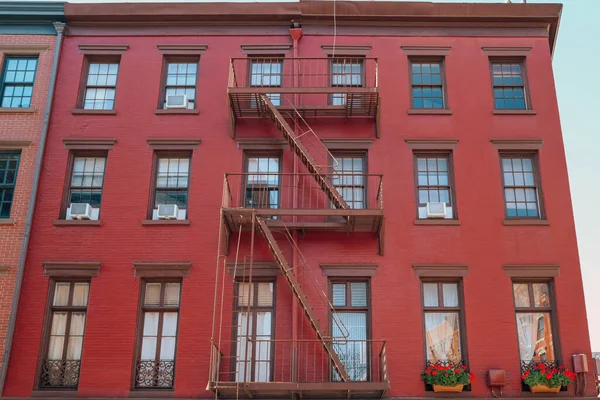 Facade of a red brick New York apartment block with fire escape at the front in Greenwich Village, New York City, USA.