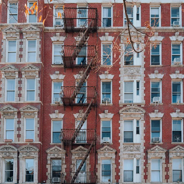 Facade of typical New York apartment blocks with fire escape at the front in New York City, USA.