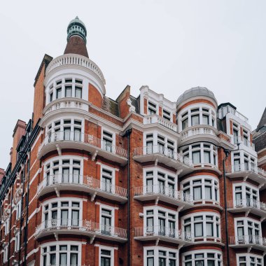 Kensington, Chelsea, Londra ve İngiltere 'de beyaz pencere çerçeveli geleneksel kırmızı tuğlalı apartman bloğu..