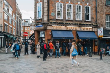 Londra, İngiltere - 13 Nisan 2023: Londra 'nın LGBTQ + barları, restoranları ve kulüpleriyle ünlü bir bölgesi olan Soho' daki Blue Posts barının önünden geçen insanlar.