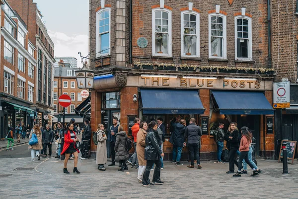 Londra, İngiltere - 13 Nisan 2023: Londra 'nın LGBTQ + barları, restoranları ve kulüpleriyle ünlü bir bölgesi olan Soho' daki Blue Posts barının önünden geçen insanlar.