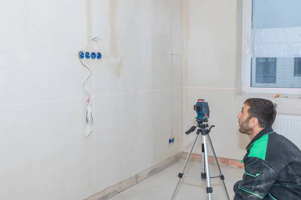 Man makes repairs in new apartment. Builder levels walls using laser level. High quality photo