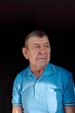 Siyah arka planda yaşlı bir adamın portresi. Yaşlı ihtiyarın düşünceli bakışı. Kırışık yüzün yakın çekimi, kopyalama alanı. Yüksek kalite fotoğraf
