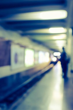Blurry image of a subway platform with human silhouette.