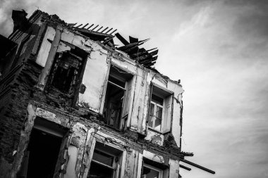 Black and white image of an abandoned and ruined old house.