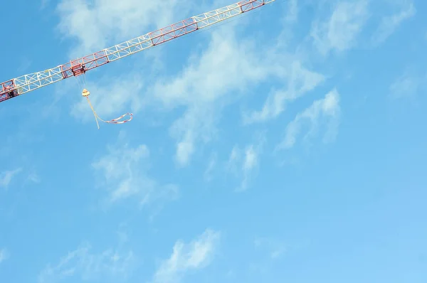 Minimalist image of a lifting crane and blue sky.