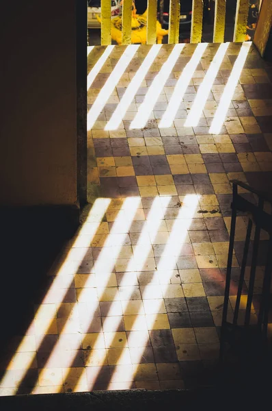 Dark hallway with bright sunlight stripes on the floor.